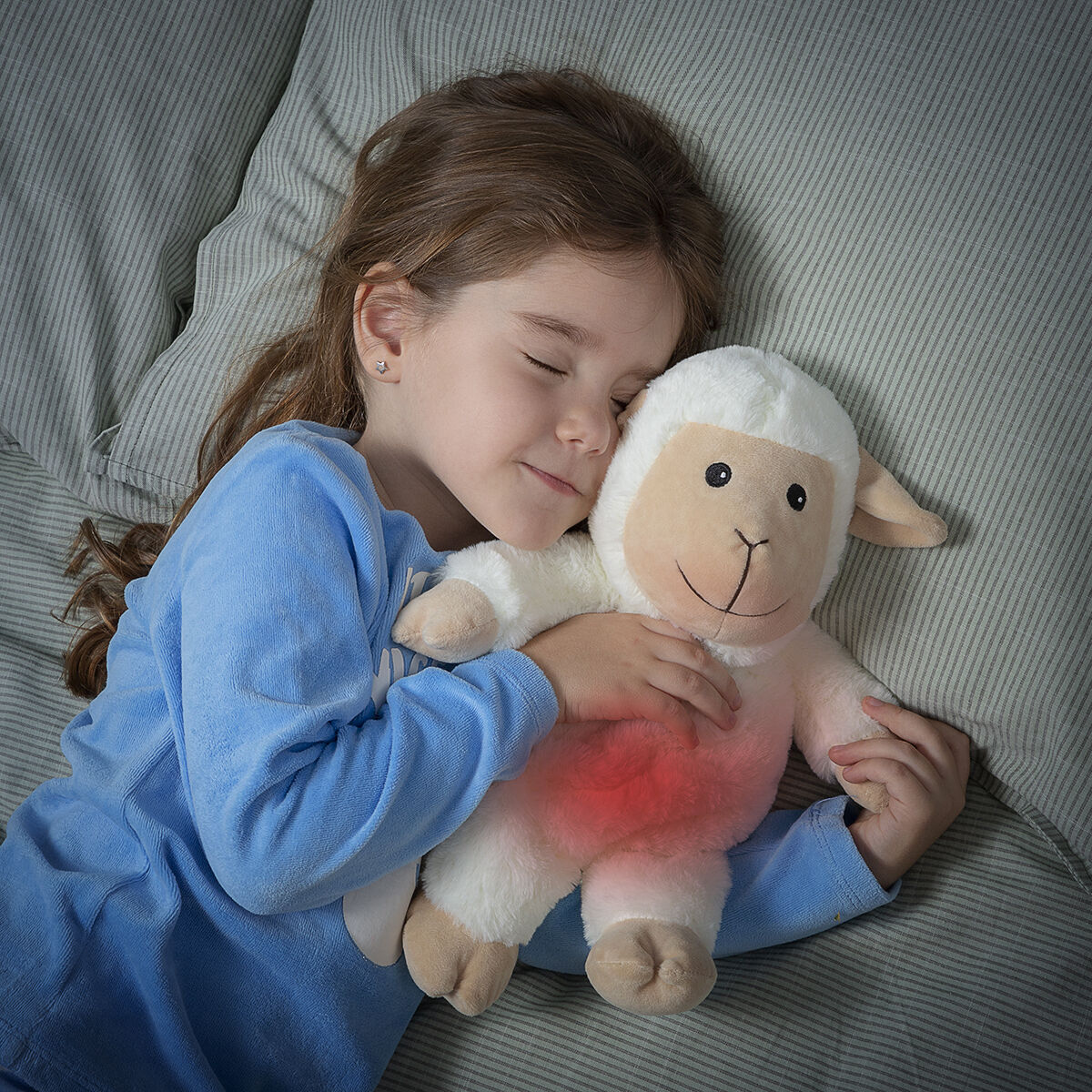 A girl sleeping peacefully with a Sheep Soft Toy with Warming and Cooling Effect Wooly InnovaGoods in her arms.