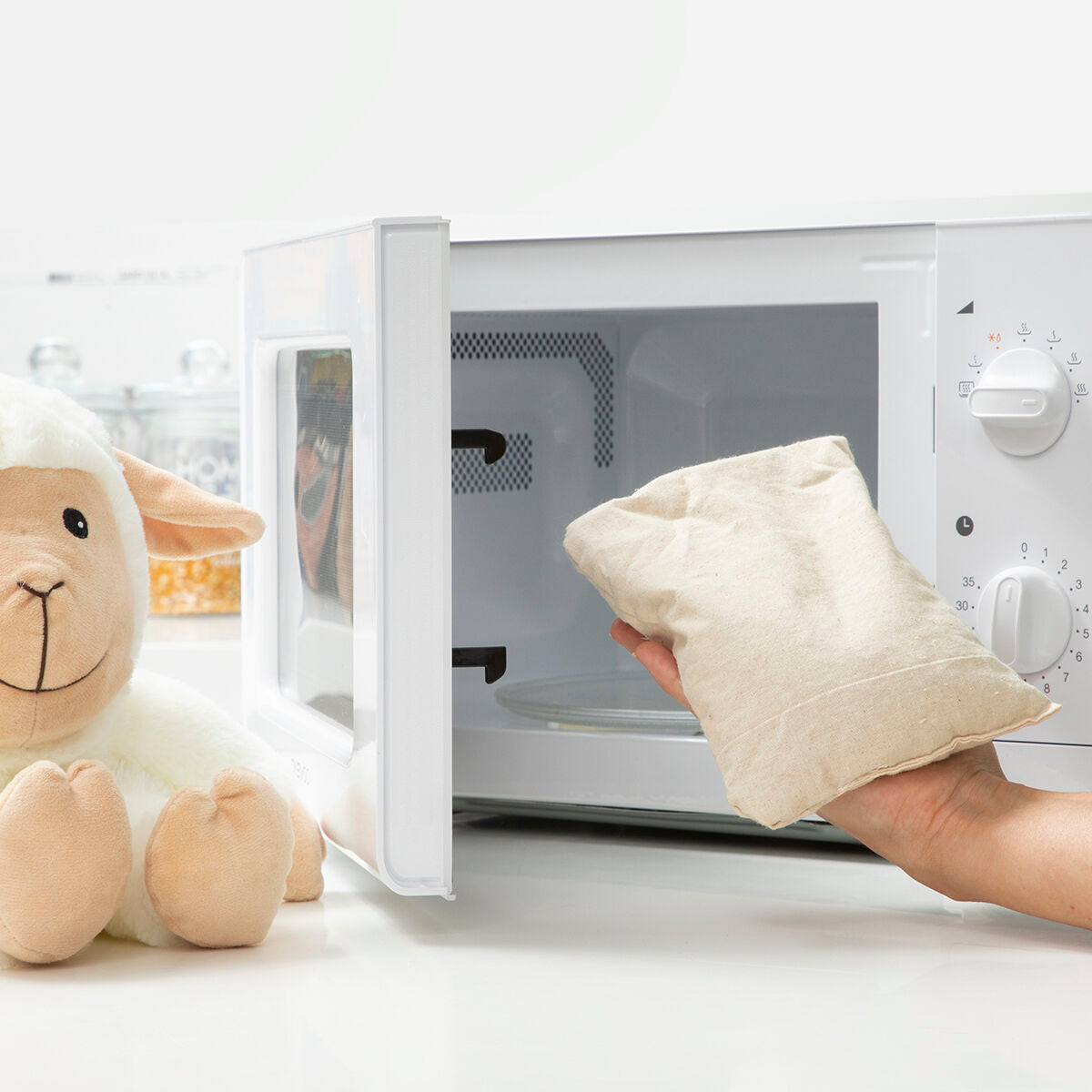 Sheep Soft Toy with Warming and Cooling Effect Wooly InnovaGoods next to a microwave for warming.