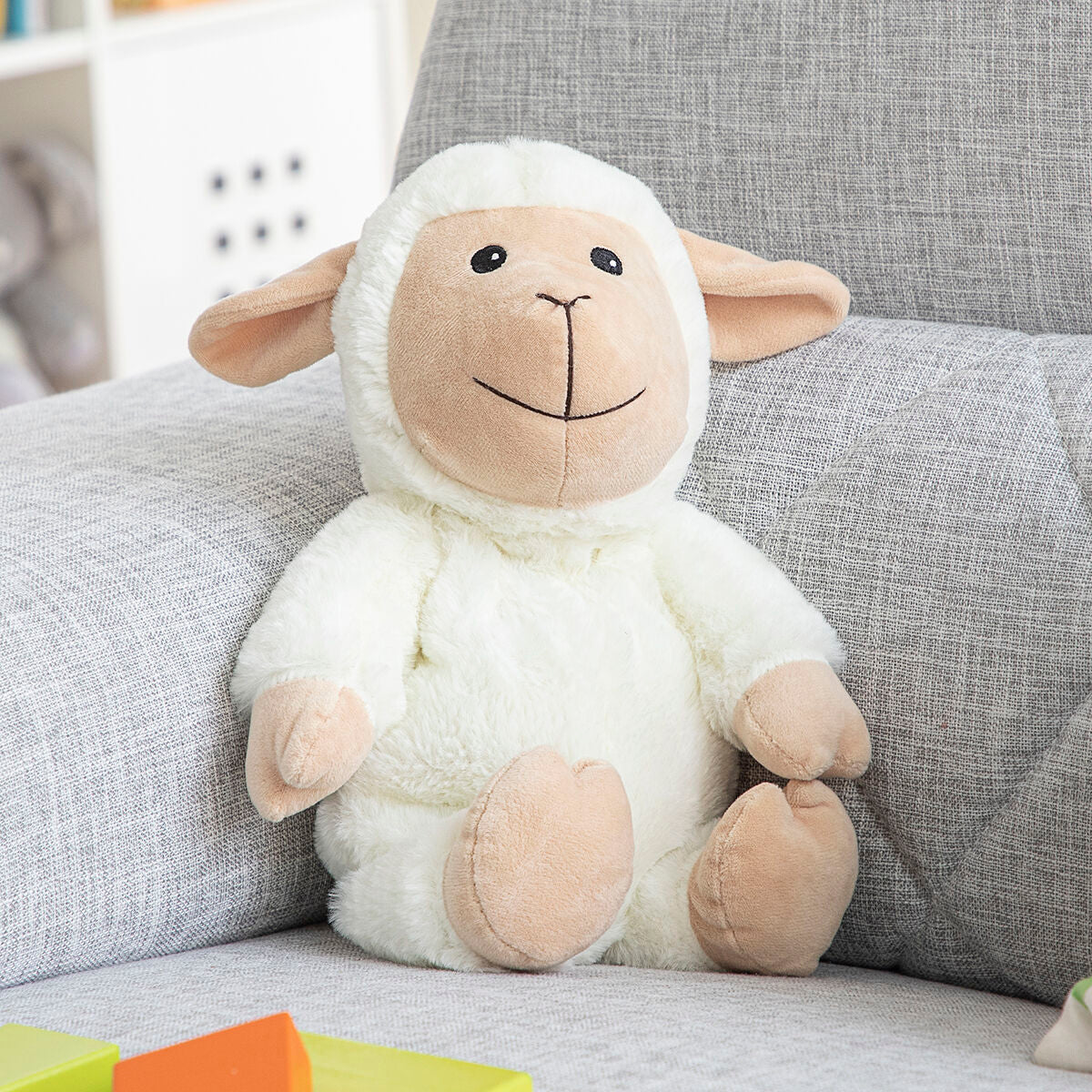 Sheep Soft Toy with Warming and Cooling Effect Wooly InnovaGoods sitting on a sofa, perfect for kids' comfort.