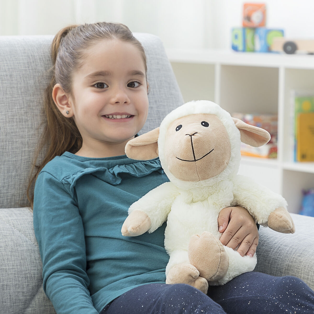 Girl holding Sheep Soft Toy with Warming and Cooling Effect Wooly InnovaGoods, smiling in a cozy setting.