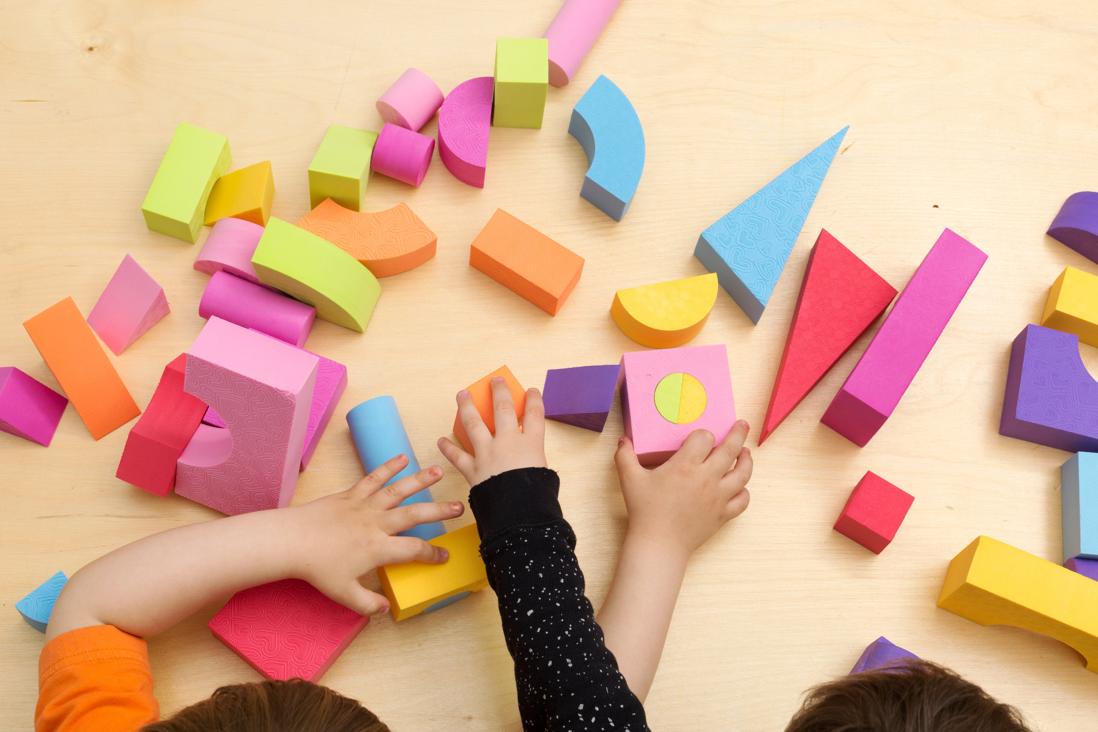 Collection of children's toys on a table with a child's arm visible reaching of one of the toys